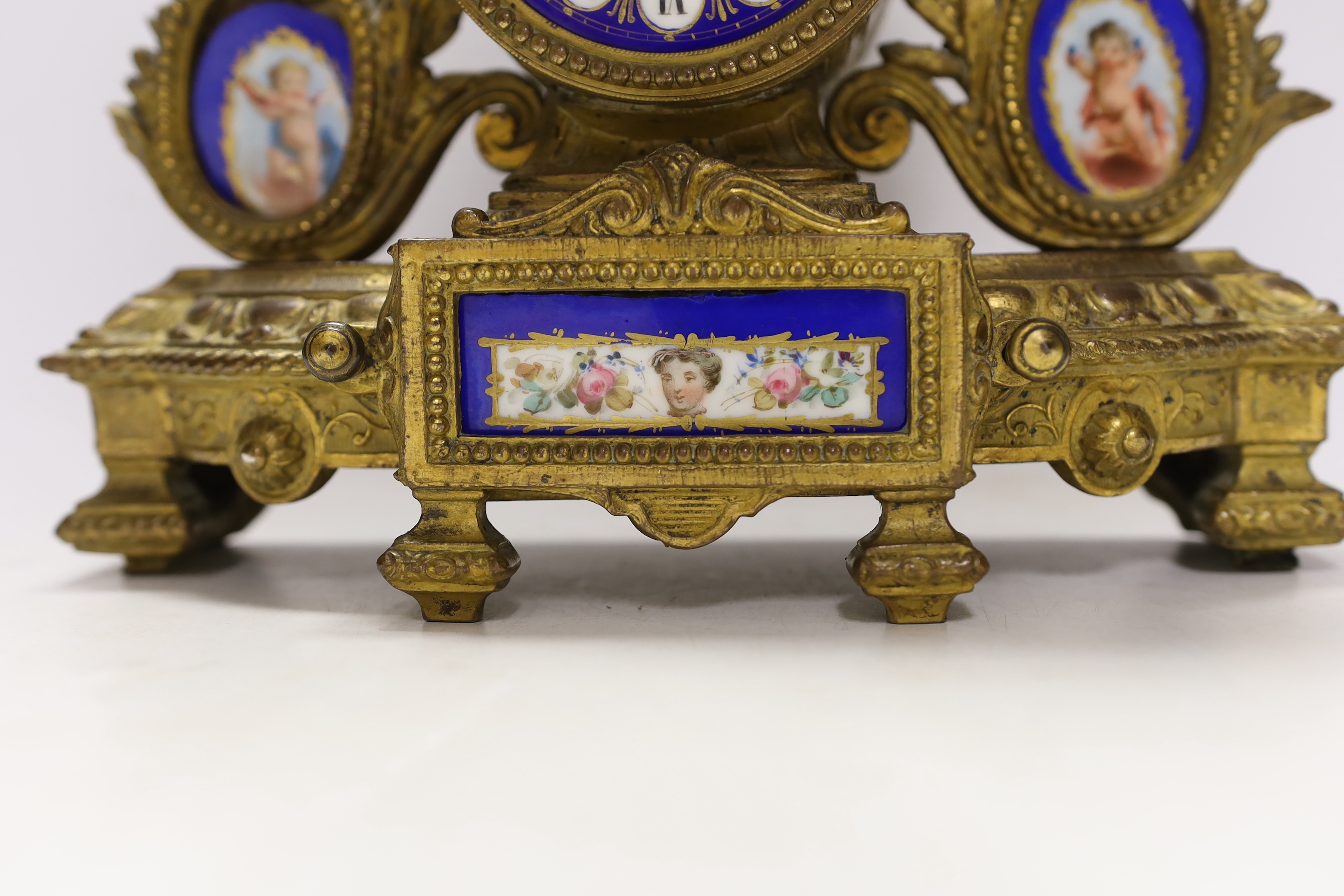 A 19th century ornate French gilt brass and porcelain clock, with two matching two branch candelabra garnitures, clock 31cm high